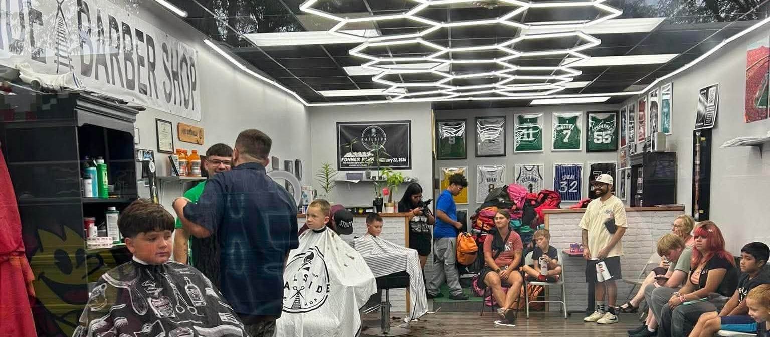 The shop on a busy afternoon — hexagon lights overhead, both chairs working and every seat in the waiting area taken.